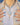 Layered necklaces against a white t-shirt with beige shirt layered over and hands either side of the jewellery